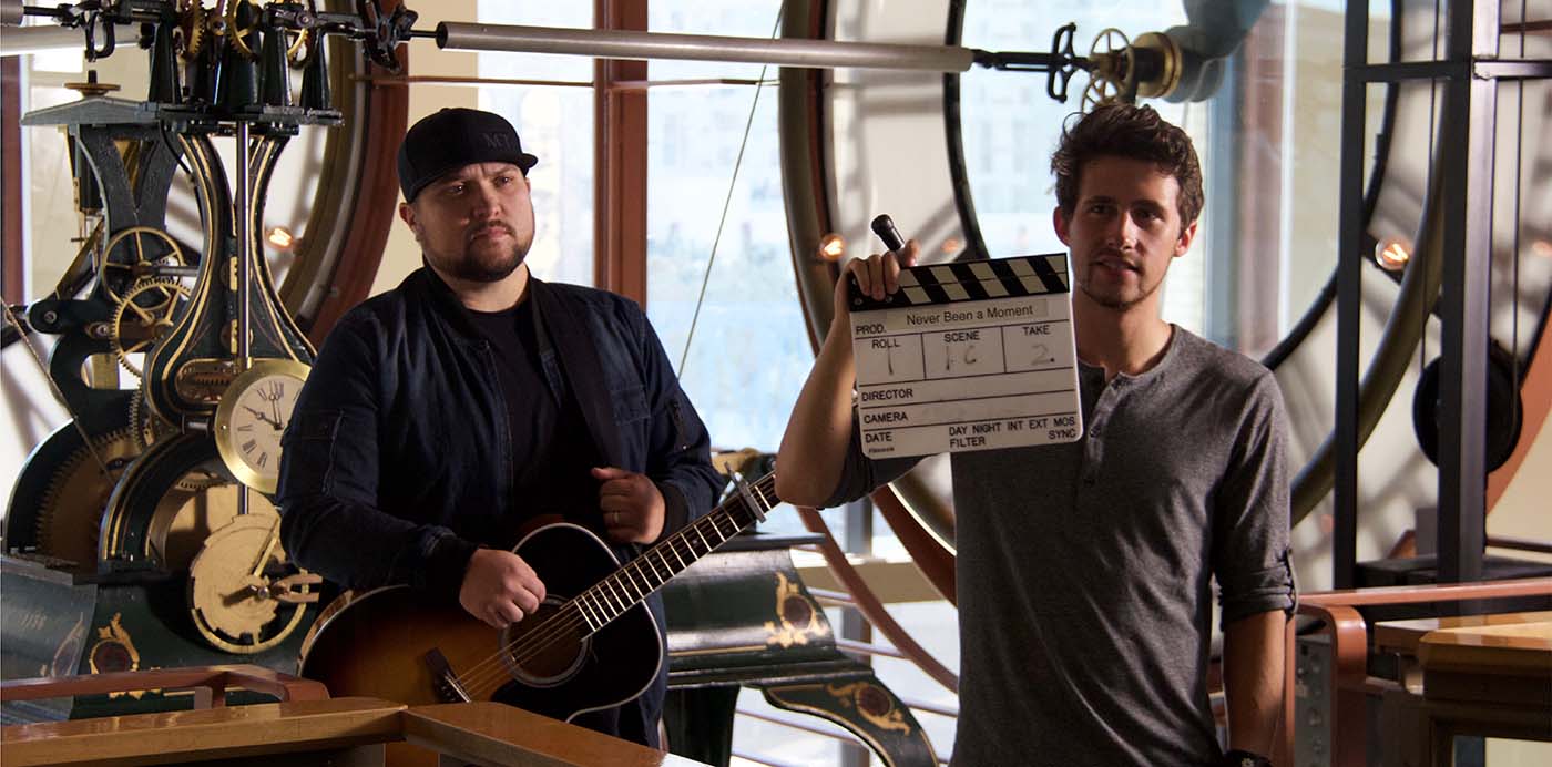 Film student holder a clapperboard in front of a man holding a guitar.