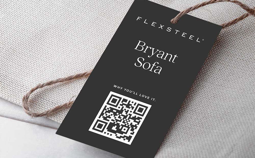 Closeup of Flexsteel Bryant Sofa tag laying on top of gray fabric